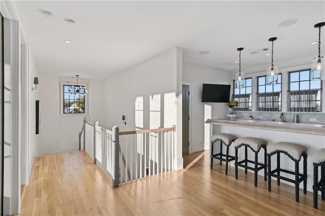 kitchen with an inviting chandelier, a kitchen bar, hanging light fixtures, and light hardwood / wood-style flooring