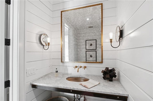 bathroom featuring wood walls and sink