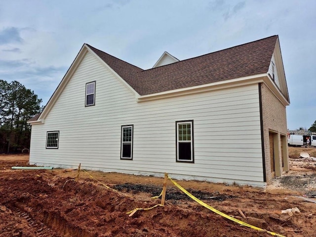 view of side of property with roof with shingles