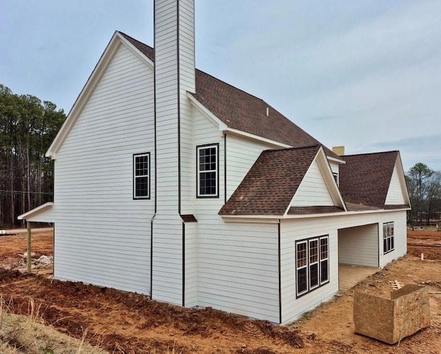 view of side of home with a chimney and a shingled roof