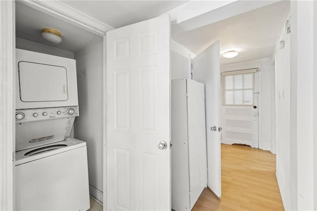 laundry room featuring stacked washer and dryer and hardwood / wood-style flooring