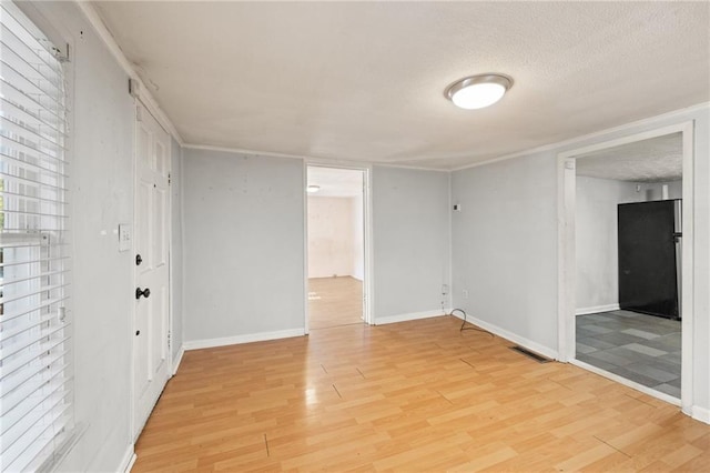 unfurnished room featuring a textured ceiling and light hardwood / wood-style floors