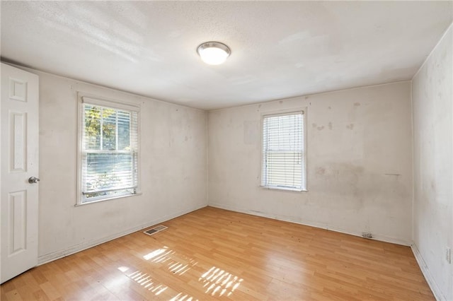 spare room featuring a textured ceiling and light hardwood / wood-style floors