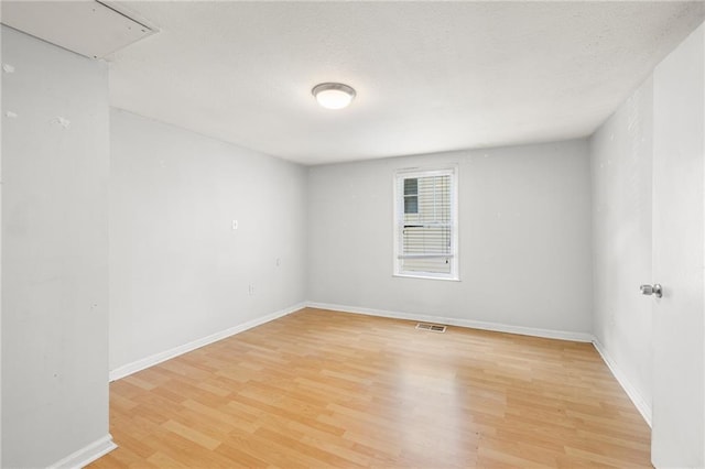 spare room with a textured ceiling and light hardwood / wood-style floors