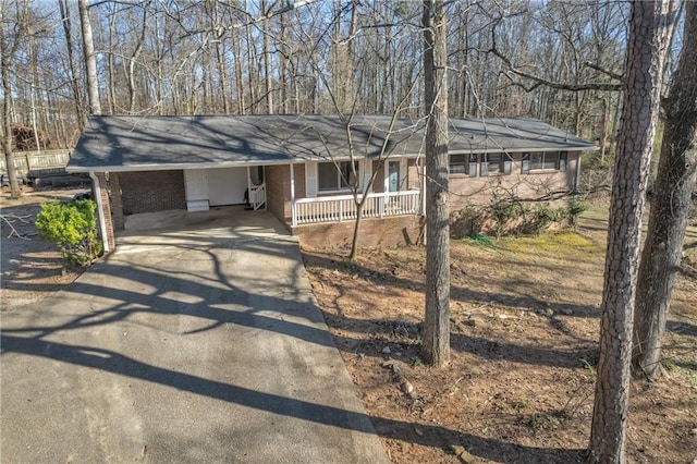 single story home featuring driveway, covered porch, and brick siding