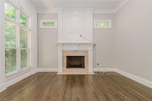 unfurnished living room with ornamental molding, dark hardwood / wood-style floors, a tiled fireplace, and a wealth of natural light