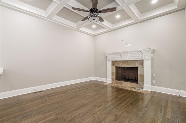 unfurnished living room featuring dark wood-type flooring, coffered ceiling, ceiling fan, beam ceiling, and a tiled fireplace