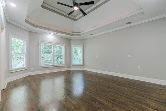 empty room with crown molding, ceiling fan, dark hardwood / wood-style floors, and a raised ceiling