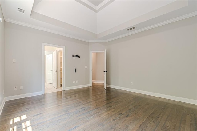 unfurnished room with a tray ceiling, hardwood / wood-style floors, and crown molding