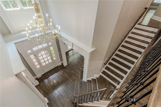 foyer entrance featuring an inviting chandelier, a towering ceiling, and dark hardwood / wood-style flooring