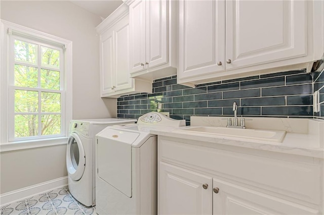 laundry room with cabinets, light tile patterned flooring, washer and dryer, and sink