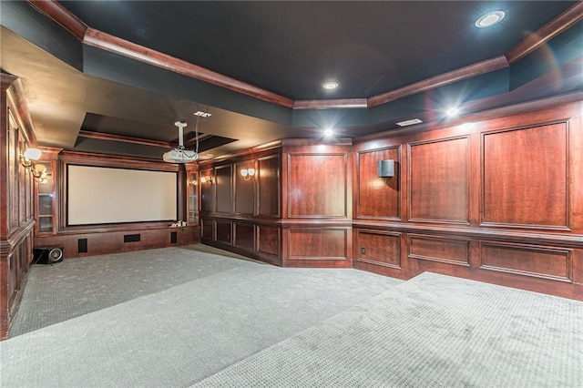 carpeted cinema room with ornamental molding and a raised ceiling