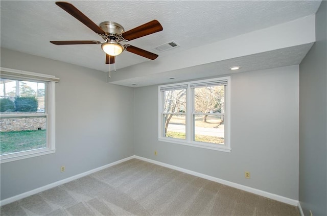 carpeted empty room with a textured ceiling, ceiling fan, and a healthy amount of sunlight