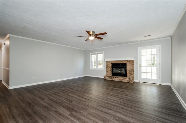 unfurnished living room with dark wood-type flooring, a textured ceiling, a brick fireplace, crown molding, and ceiling fan