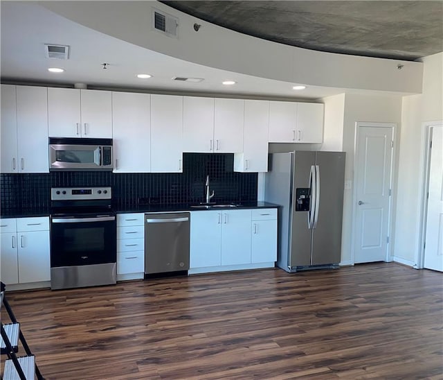 kitchen featuring appliances with stainless steel finishes, sink, dark wood-type flooring, and white cabinets