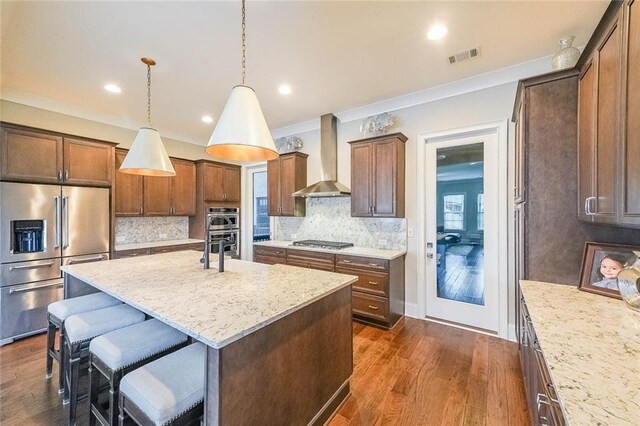 6626 Sterling Dr, Sandy Springs, GA 30328 - kitchen featuring stainless steel appliances, wall chimney exhaust hood, an island with sink, backsplash, and a breakfast bar area