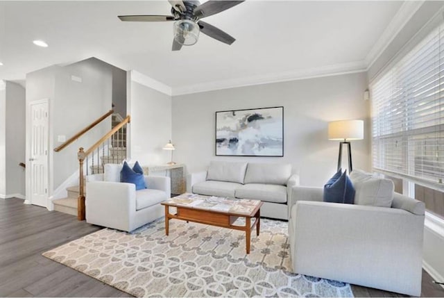 living area featuring ornamental molding, wood finished floors, baseboards, ceiling fan, and stairs