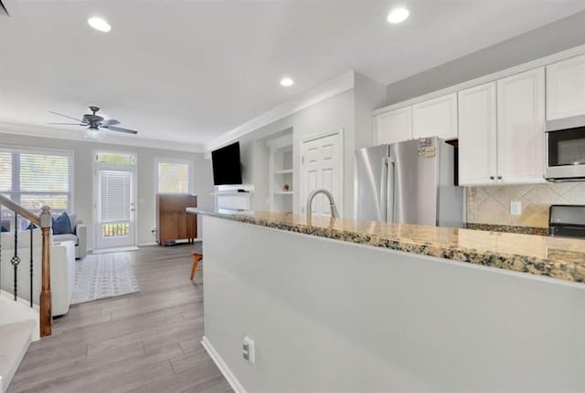 kitchen featuring white cabinetry, light stone counters, a ceiling fan, and stainless steel appliances