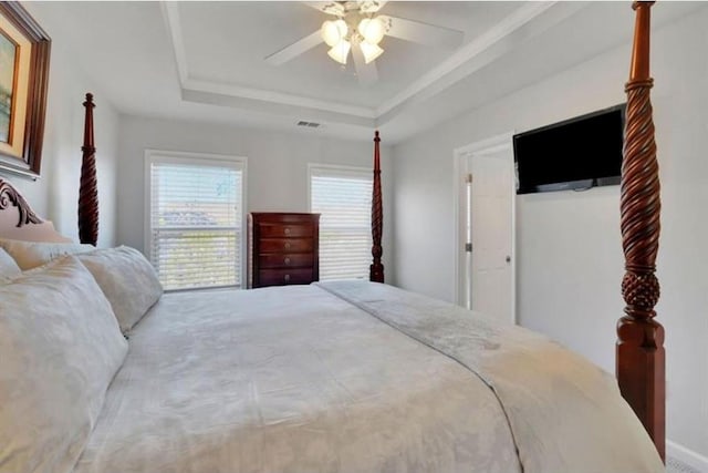 bedroom featuring visible vents, a raised ceiling, and a ceiling fan