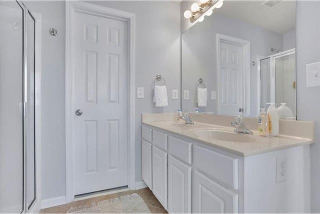 full bathroom with tile patterned flooring, visible vents, a shower stall, double vanity, and a sink