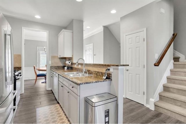 kitchen featuring stainless steel refrigerator, a sink, stone countertops, wood finished floors, and white cabinetry