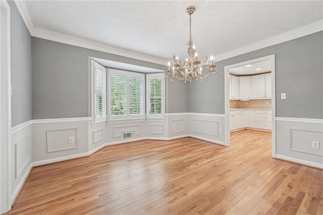 2655 Nesbit Trl, Alpharetta, GA 30022 - unfurnished dining area with a chandelier, light wood-type flooring, ornamental molding, wainscoting, and a decorative wall
