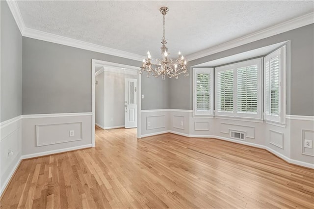 2655 Nesbit Trl, Alpharetta, GA 30022 - unfurnished dining area featuring a chandelier, light wood-style flooring, wainscoting, a textured ceiling, and crown molding
