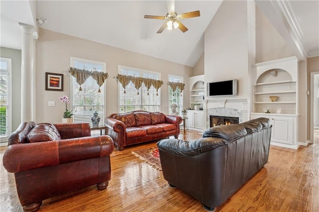 living area featuring a high end fireplace, light wood-style flooring, built in shelves, and ceiling fan
