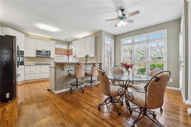 dining room with baseboards, a ceiling fan, and light wood-style floors