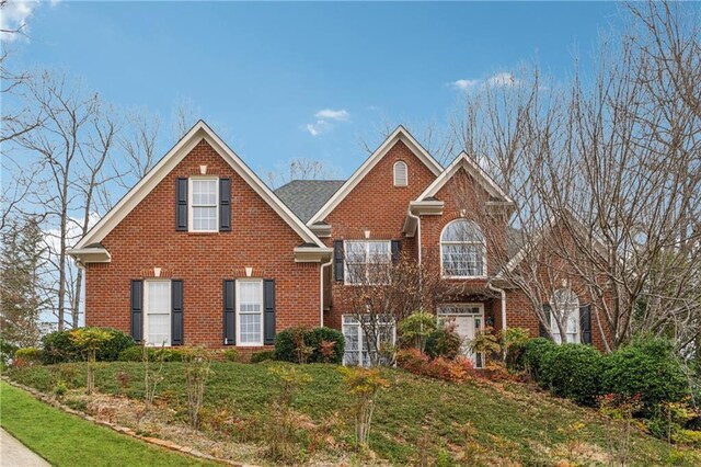 traditional-style home featuring brick siding and a front yard