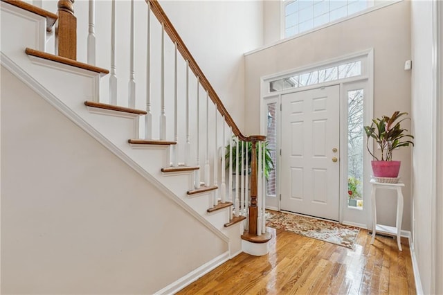 entrance foyer featuring stairway, wood finished floors, baseboards, and a towering ceiling