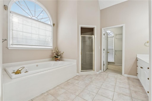 full bath with a spacious closet, a shower stall, a garden tub, tile patterned floors, and vanity