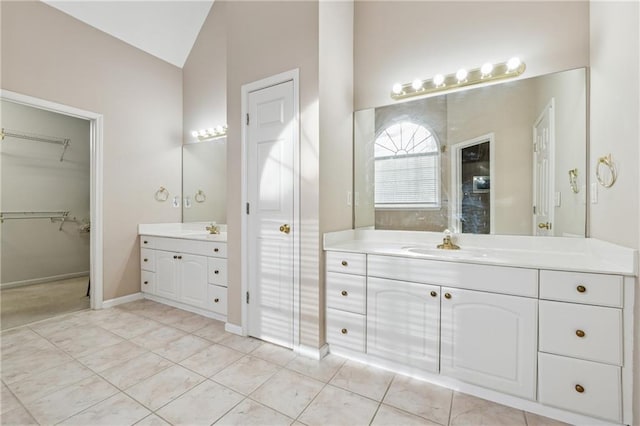 bathroom featuring tile patterned flooring, walk in shower, lofted ceiling, two vanities, and a sink
