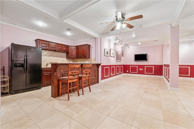 kitchen with backsplash, beamed ceiling, ornamental molding, a kitchen breakfast bar, and black fridge with ice dispenser