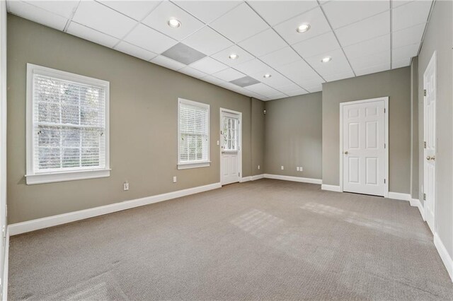 carpeted empty room with recessed lighting, baseboards, and a drop ceiling