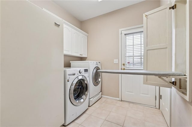 clothes washing area with light tile patterned floors, washer and dryer, and cabinet space