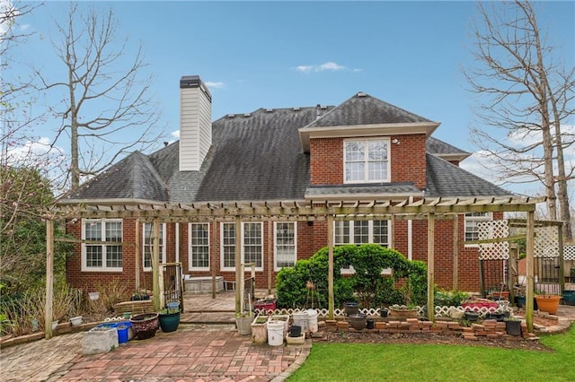 rear view of property featuring roof with shingles, a pergola, a chimney, a patio area, and brick siding