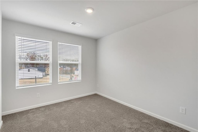 carpeted empty room featuring visible vents and baseboards