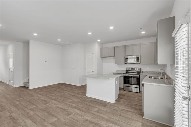 kitchen with a sink, gray cabinets, a center island, stainless steel appliances, and recessed lighting