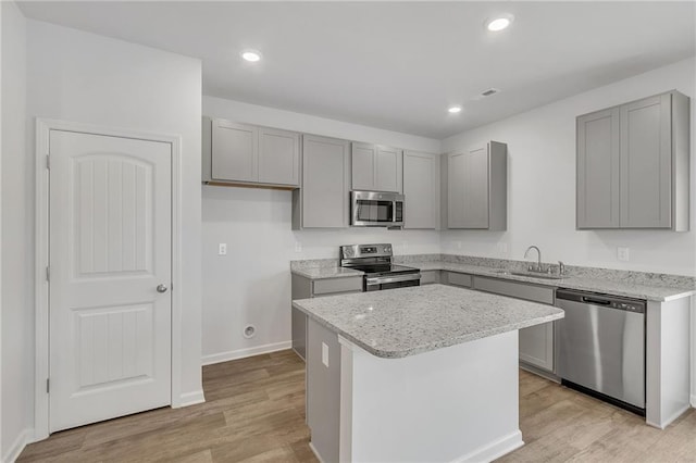 kitchen with a center island, a sink, gray cabinets, and stainless steel appliances