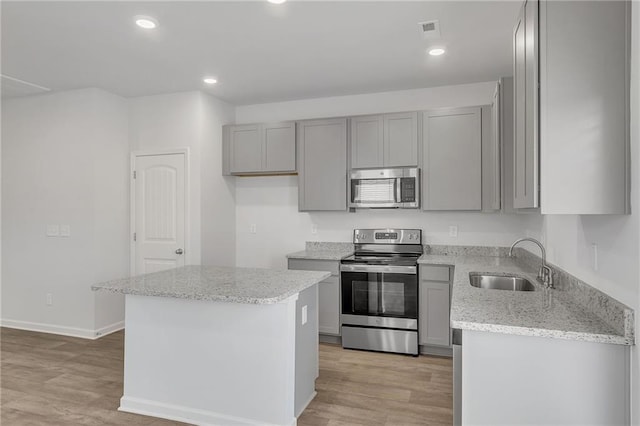 kitchen with light wood-style floors, a sink, appliances with stainless steel finishes, and gray cabinetry