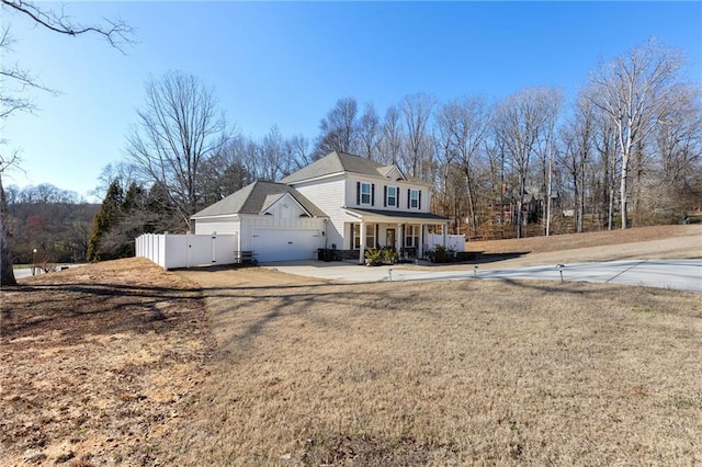 view of front of home featuring covered porch, concrete driveway, a front yard, and fence