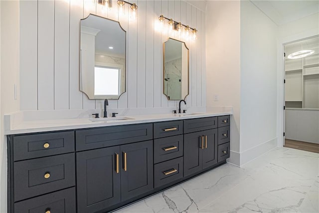 bathroom featuring marble finish floor, a sink, double vanity, and baseboards