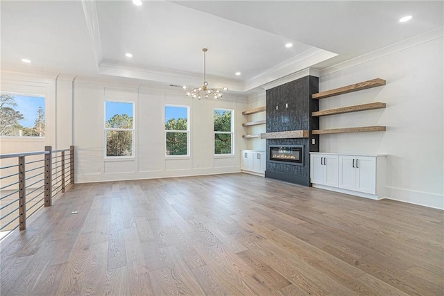 unfurnished living room with light wood-type flooring, plenty of natural light, ornamental molding, and a notable chandelier