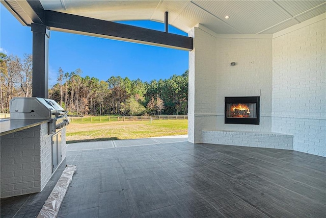 view of patio / terrace featuring fence, exterior kitchen, grilling area, and an outdoor brick fireplace