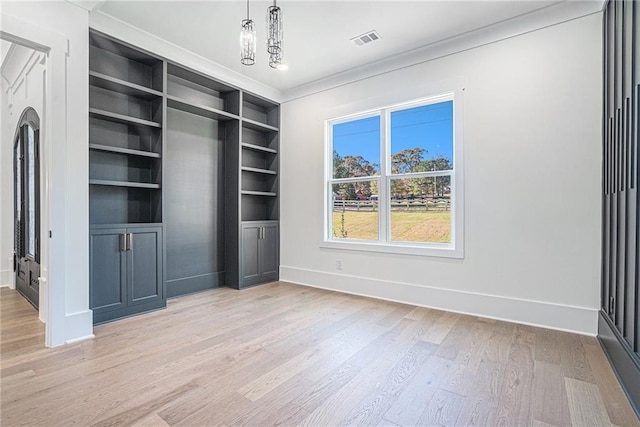 unfurnished bedroom with crown molding, visible vents, baseboards, light wood finished floors, and a notable chandelier
