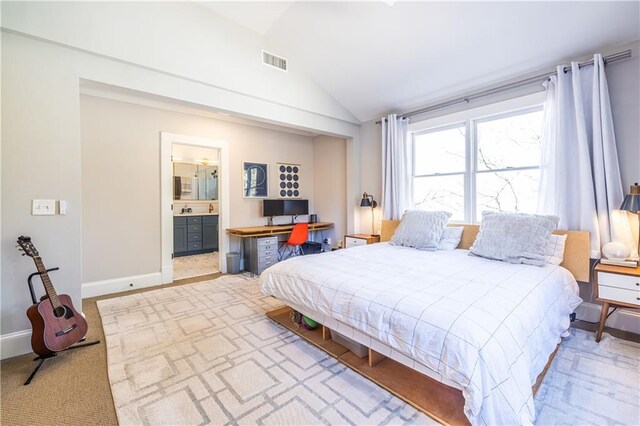 bedroom with lofted ceiling, visible vents, baseboards, and ensuite bathroom