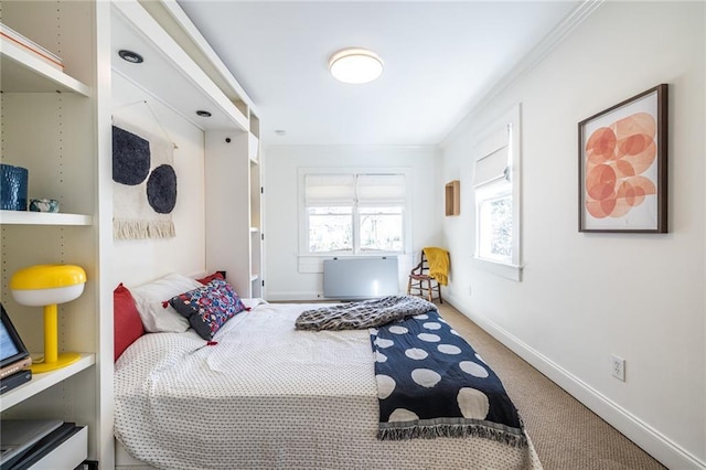 carpeted bedroom with ornamental molding and baseboards