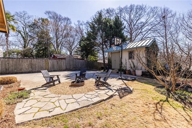 view of patio with a fenced backyard, a fire pit, and an outbuilding