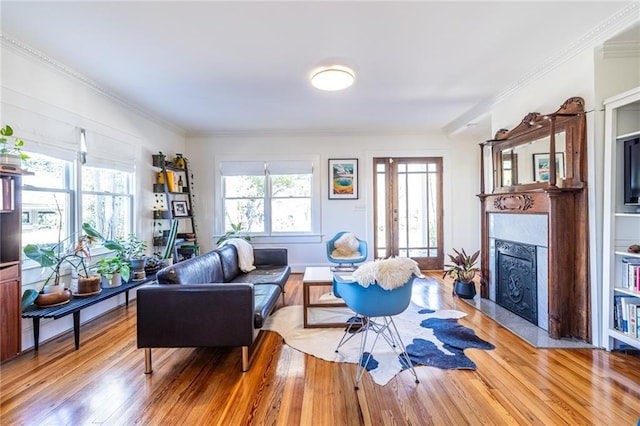 living room with light wood-style flooring, crown molding, and a fireplace with flush hearth